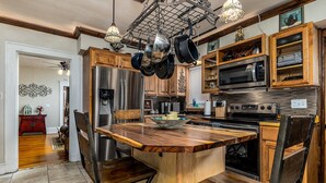 A modern kitchen with wooden cabinetry, stainless steel appliances, and a central island with chairs. - Elegant 2 BR With Stunning Kitchen Prime Location! (Dubuque)