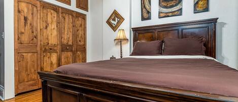 Ein Schlafzimmer mit einem großen Holzbett, einem Holzschrank und einem Nachttisch mit Lampe.