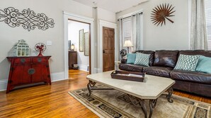 A living room with a brown leather sofa, a red wooden cabinet, and a cream-colored coffee table. - Elegant 2 BR With Stunning Kitchen Prime Location! (Dubuque)
