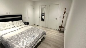 Ein Schlafzimmer mit Bett, Nachttisch, Spiegel und Kleiderständer.
