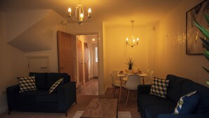 A living room with two sofas, a coffee table, and a chandelier. There is a dining area with a table and chairs in the background. - Spacious 3 bed  town house in Bristol. (Bristol)