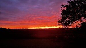 Ein Sonnenuntergang über einer ebenen Landschaft mit Baum-Silhouetten und einem klaren Horizont.