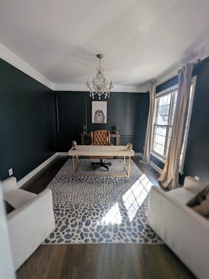 Un comedor con mesa, sillas, una araña y una ventana con cortinas.