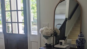 A dark wooden dresser with a mirror, a vase with white flowers, a small figurine, and a decorative vase. - Southern charm meets Lake Norman/Charlotte - pet friendly (Cornelius)