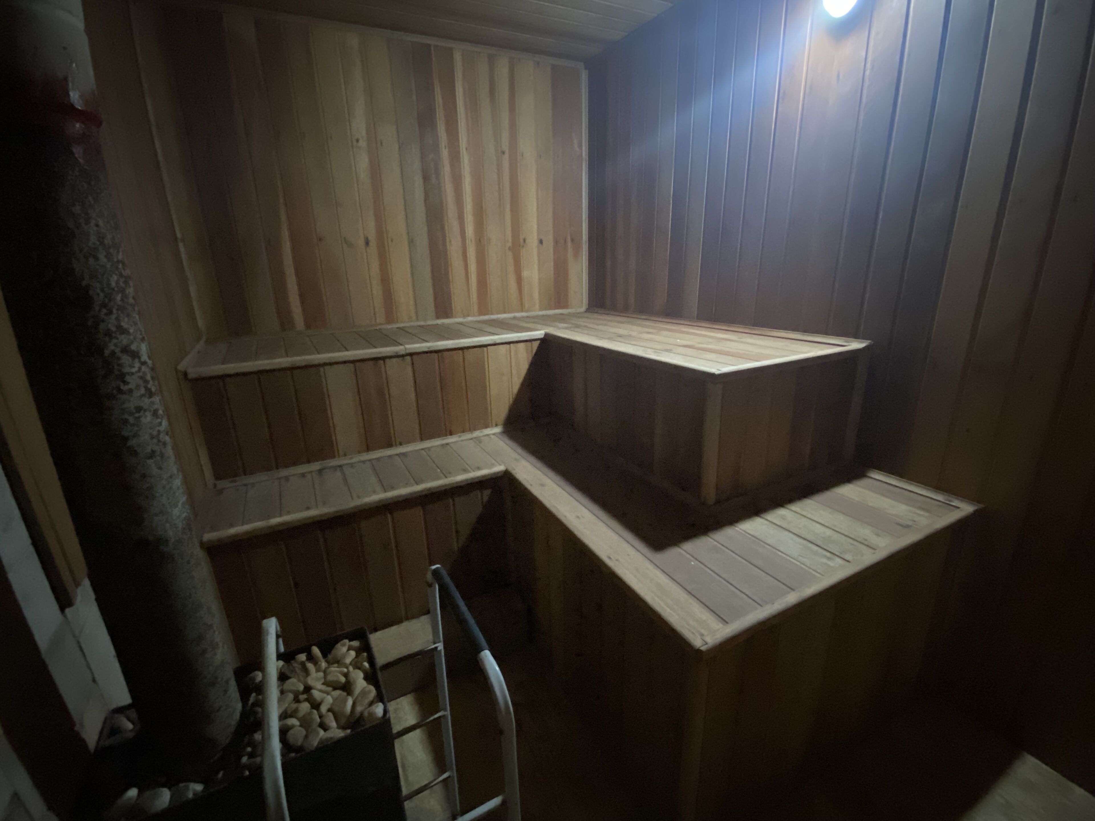Un sauna avec des bancs en bois et une échelle en métal.