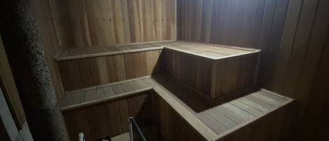 Un sauna avec des bancs en bois et une échelle en métal.