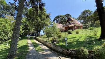 Uma casa com telhado vermelho e uma varanda, cercada por árvores e um gramado.