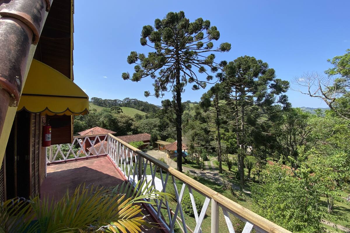 A balcony with a view of a forested hillside and a clear blue sky.