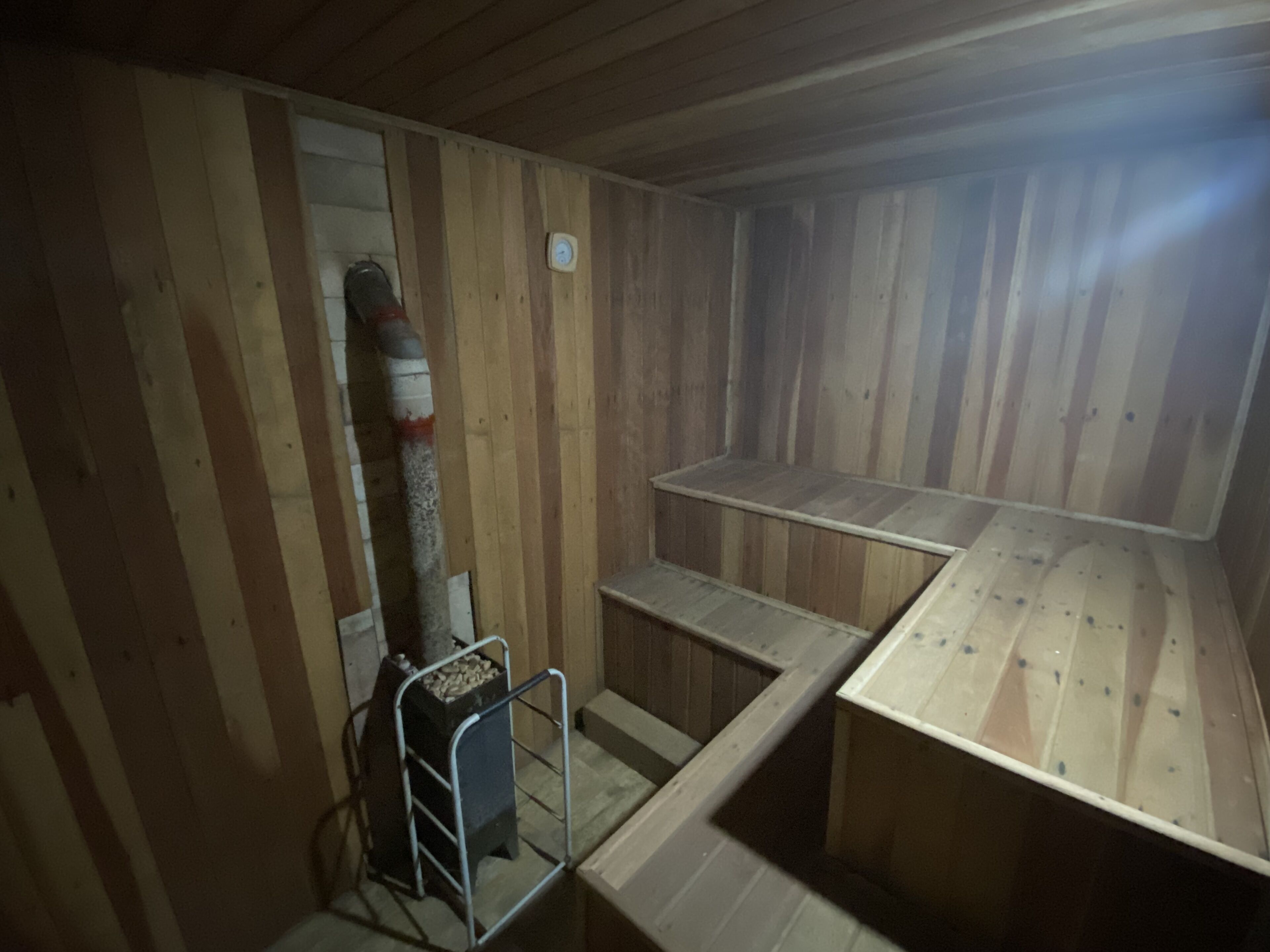 Un sauna con paredes de madera, un banco y un calentador.