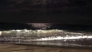 A nighttime beach scene with waves crashing onto the shore and a single light source illuminating the water. - Beautiful Galveston, ocean front, Ocean views, Comfortable Beds N Amazing pools. (Galveston)