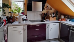 Una cocina compacta con horno integrado, cafetera y licuadora sobre la encimera.