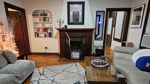 A living room with a fireplace, a sofa, a coffee table, and a bookshelf. - 2 Blocks to UF Campus in Midtown & 10min Walk to Ben Griffin Stadium, Free Wi-Fi (Gainesville)