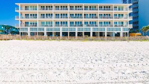 Een hotel met meerdere verdiepingen en balkons, gelegen aan een zandstrand.