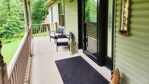 Een veranda met een bord dat welkom zegt, een beeldje van een hond en een bank.