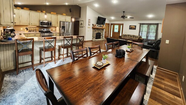 Een ruime keuken met moderne apparatuur, een eetgedeelte met houten meubels, en een gezellige woonkamer met open haard.