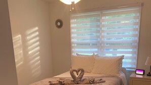 A bedroom with a bed, a nightstand, a clock, and a ceiling fan. - Cozy Matthews House in a Convenient Location (Matthews)