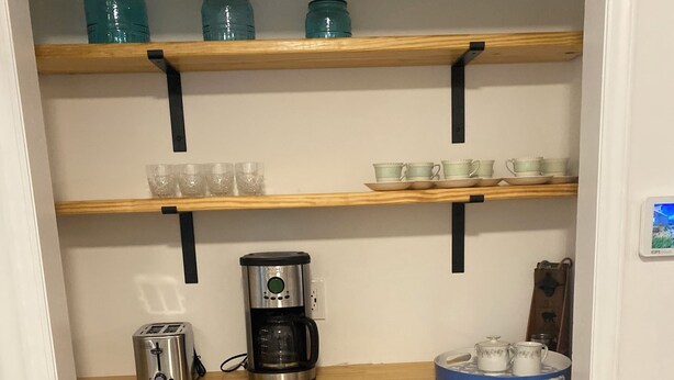 A kitchen with wooden shelves, a coffee maker, and wicker baskets. - Cozy Matthews House in a Convenient Location (Matthews)