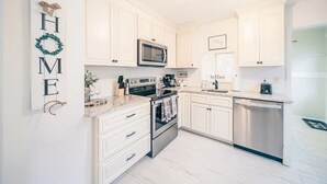 Una cocina moderna con armarios blancos, electrodomésticos de acero inoxidable y un letrero que dice 'HOME'.