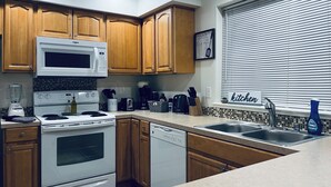 Una cocina moderna con armarios de madera, un microondas integrado, una estufa y un lavavajillas.