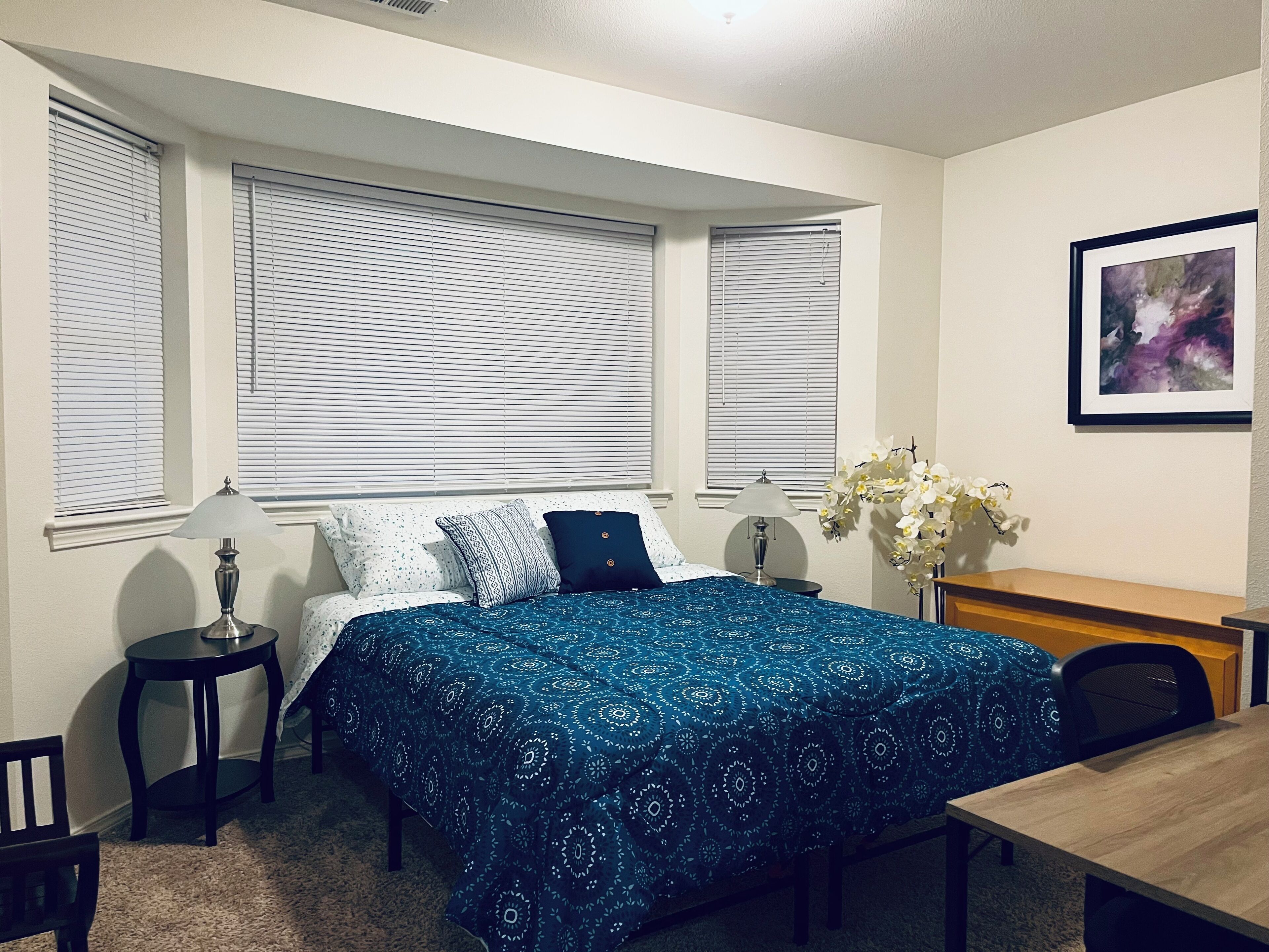 A bedroom with a bed, two bedside tables, a desk, and a chair.