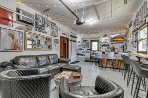 Un rincón de sala cómodo con un sofá de cuero, una mesita redonda y una zona de bar con taburetes.