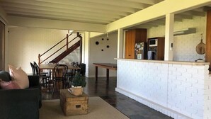 Et moderne køkken med hvide murstensvægge, en trætrappe og et spiseområde med bord og stole.