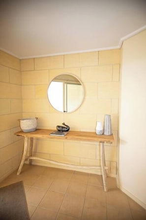 Ein Badezimmer mit einem Holzkosmetikschrank, einem runden Spiegel und einem Handtuchhalter.