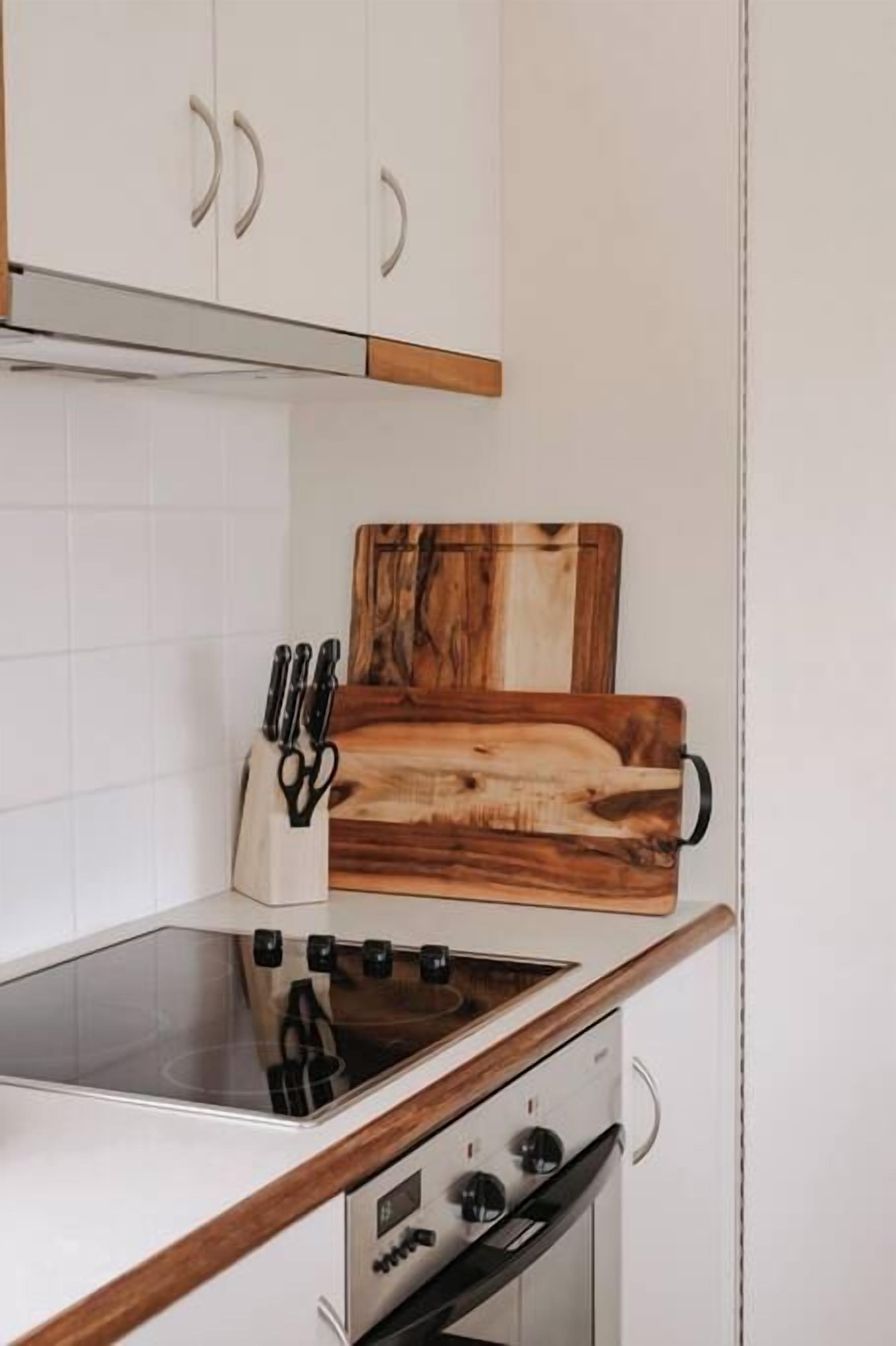 A kitchen with white cabinets, a wooden countertop, a cutting board, and a knife block.