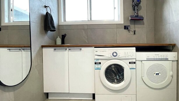 A laundry room with a washing machine and dryer, a towel rack, and a window. - The Hangout KING BEDS Hammock Chairs with a View (Port Campbell)