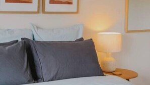 A hotel room with a bed, pillows, a bedside lamp, and two framed artworks on the wall. - The Hangout KING BEDS Hammock Chairs with a View (Port Campbell)