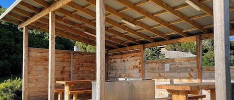 Un espace extérieur abrité, doté de bancs en bois et d’un évier central.