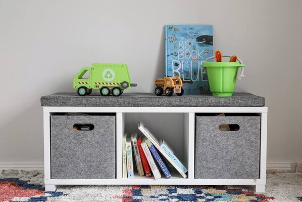 A white storage unit with grey bins and a green toy truck on top.