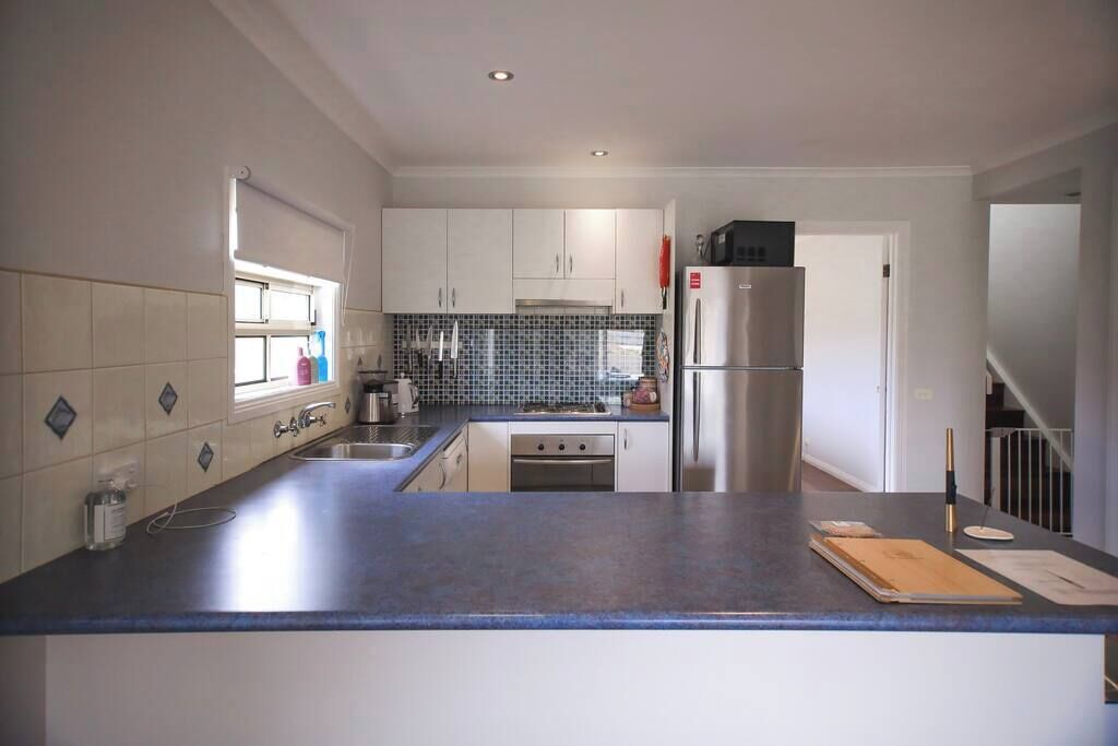 Een moderne keuken met witte kasten, een roestvrijstalen koelkast en een blauw aanrecht.