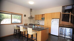 Una cocina moderna con una isla central, taburetes de bar, un refrigerador y un microondas.