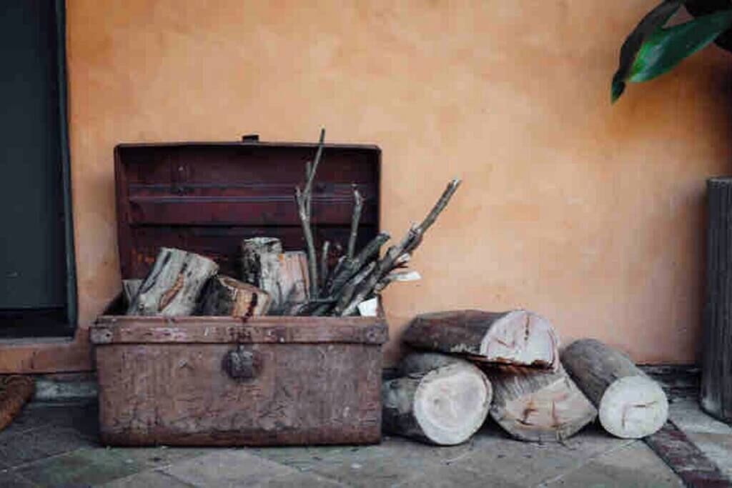 A wooden chest filled with firewood and logs against a wall.