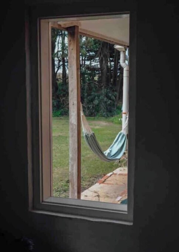 A window with a view of a hammock hanging outside.