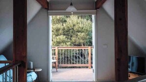 A room with a wooden ceiling, a sliding glass door leading to an outdoor deck with a railing, and a ceiling fan. - Woodlands - Secluded Rustic Cottage Near Great Ocean Road (Port Campbell)