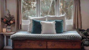 A cozy room with a window seat, a wooden chest, and a vase with flowers. - Woodlands - Secluded Rustic Cottage Near Great Ocean Road (Port Campbell)
