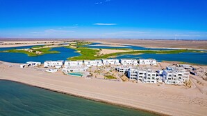 An aerial view of a coastal resort with multiple white buildings, a marina, and a large body of water. - Blue House LV 2-4 Costa Divina by Kivoya (Puerto Peñasco)