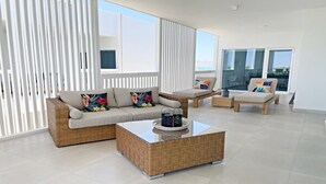 A modern living room with a wicker sofa, a coffee table, and two armchairs. - Blue House LV 2-4 Costa Divina by Kivoya (Puerto Peñasco)
