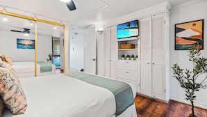 Une chambre à coucher avec un lit, une télévision, une armoire et une plante.