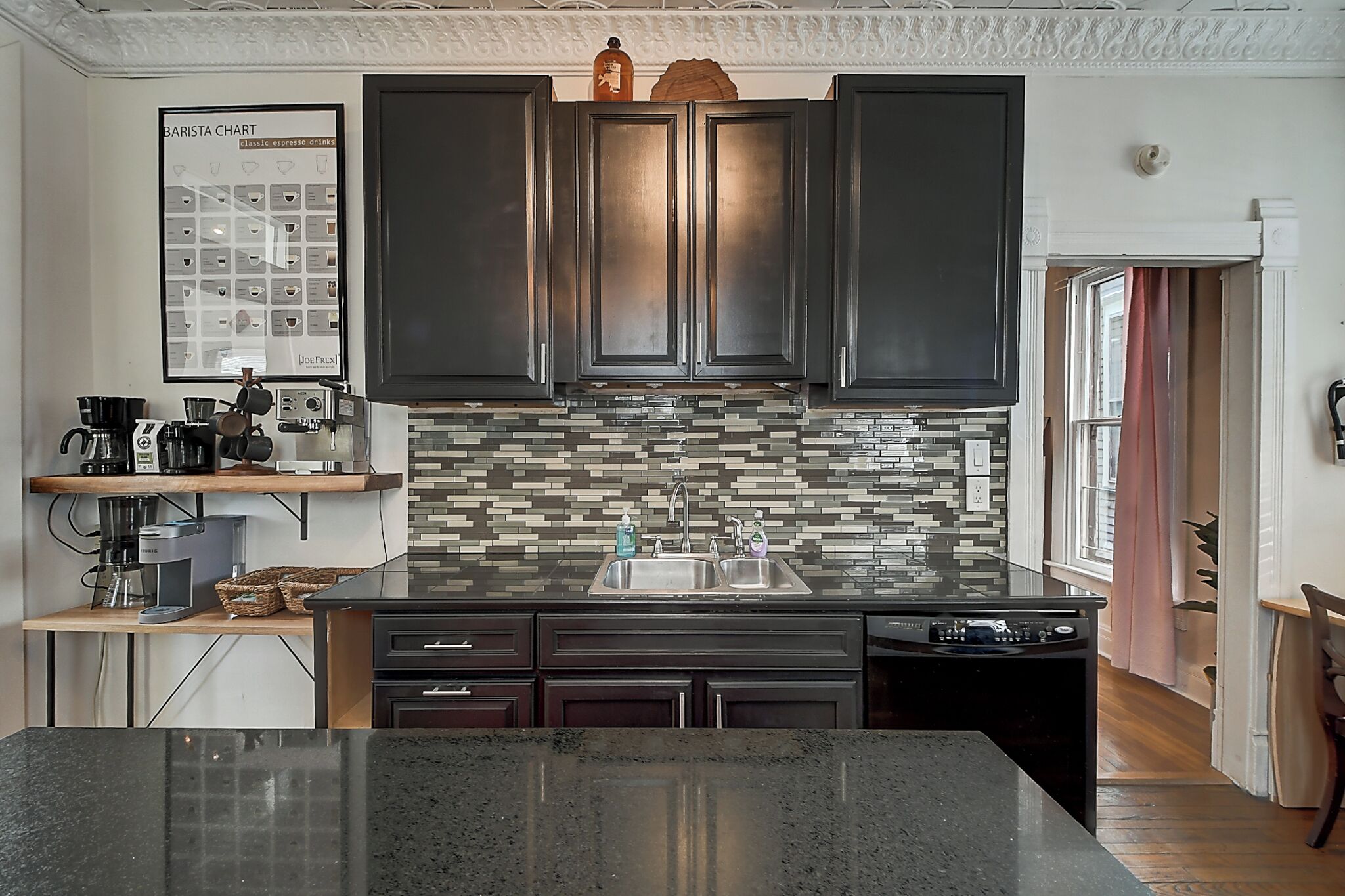 Uma cozinha moderna com armários escuros, painel de azulejos e uma ilha central.