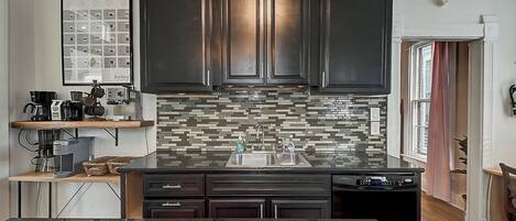 Uma cozinha moderna com armários escuros, painel de azulejos e uma ilha central.