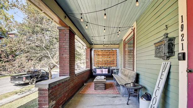A porch with a brick column, a bench, a table with a kettle, and a welcome sign. - Historic Talbott Street Home-Hot Tub and Fire Pit! (Indianapolis)