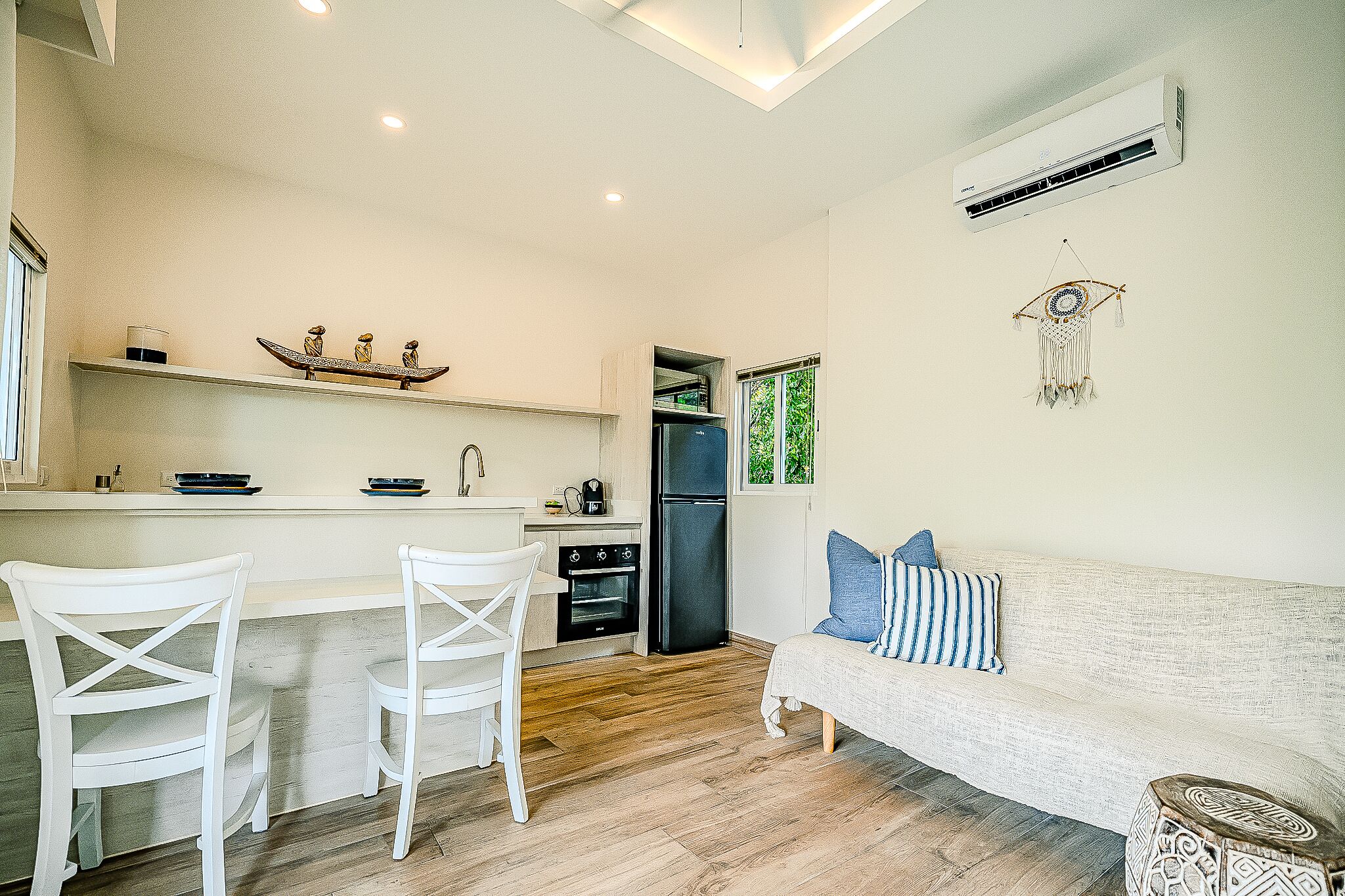 A compact kitchen with a refrigerator, oven, and a window overlooking greenery.