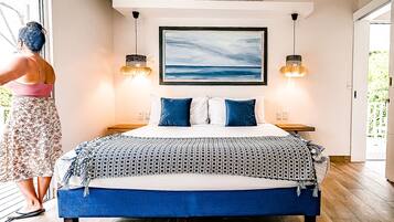 Une chambre à coucher avec un lit, deux tables de chevet, un tableau au mur et deux lampes suspendues.