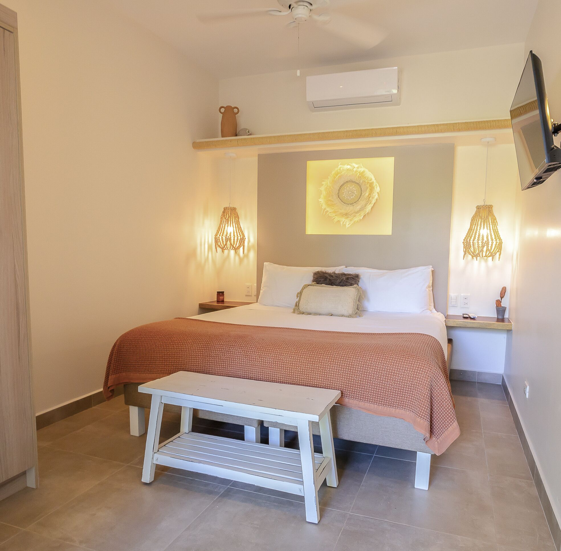 A bedroom with a bed, bedside lamps, a TV, and a ceiling fan.