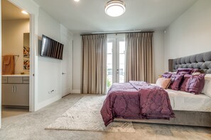 Una camera da letto con un letto, tende, una televisione a schermo piatto e un bagno con portascopevoli.