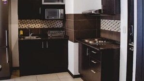 A compact kitchen with dark cabinetry, a microwave, a stove, and a sink. - Puerto Santa Ana , automatic check in, Parking (Guayaquil)