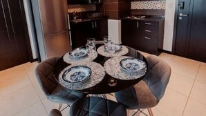 A modern kitchen with dark cabinetry, a stainless steel refrigerator, and a dining area with a round table and four chairs. - Puerto Santa Ana , automatic check in, Parking (Guayaquil)